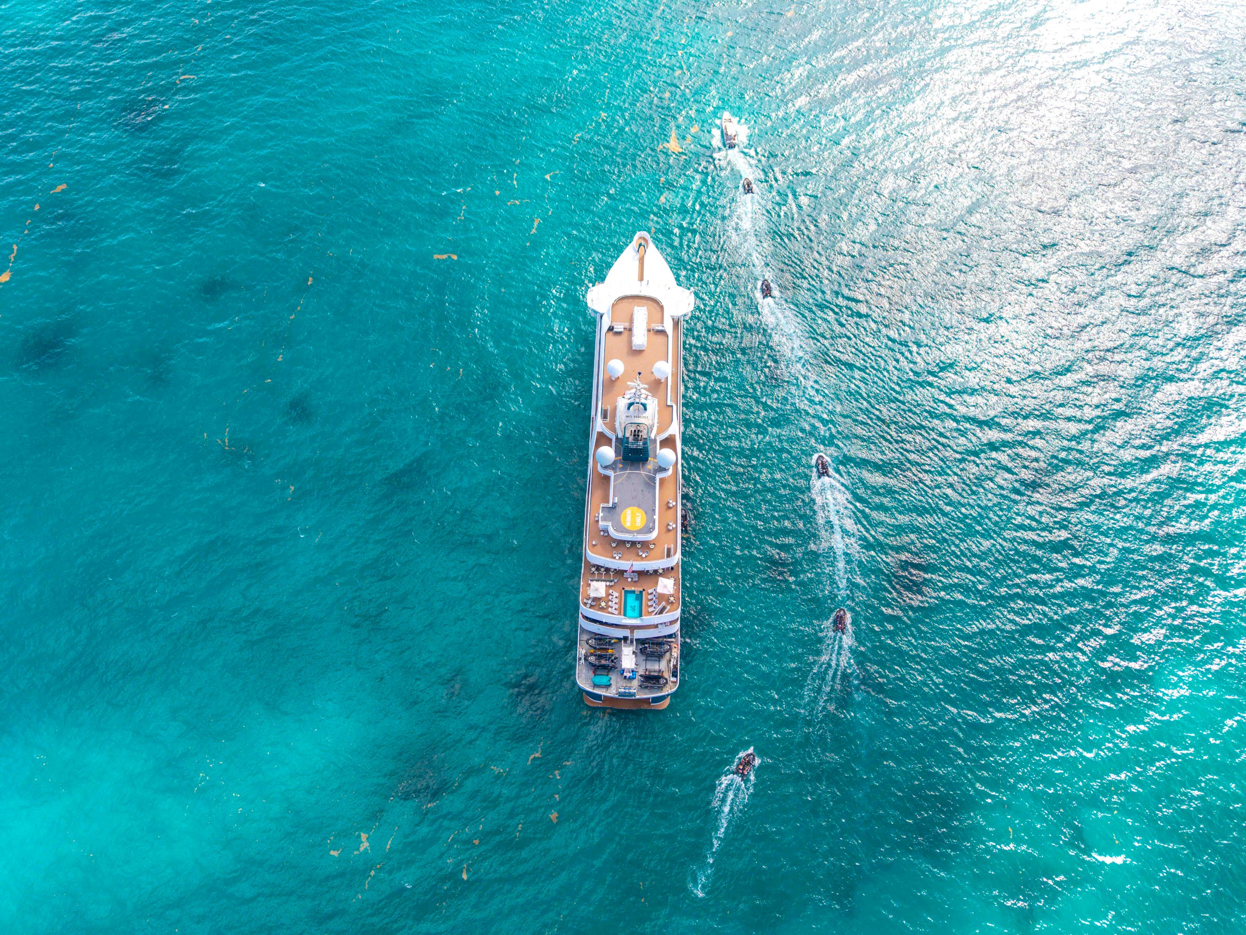Aerial view of a Swan Hellenic expedition megayacht sailing through turquoise waters