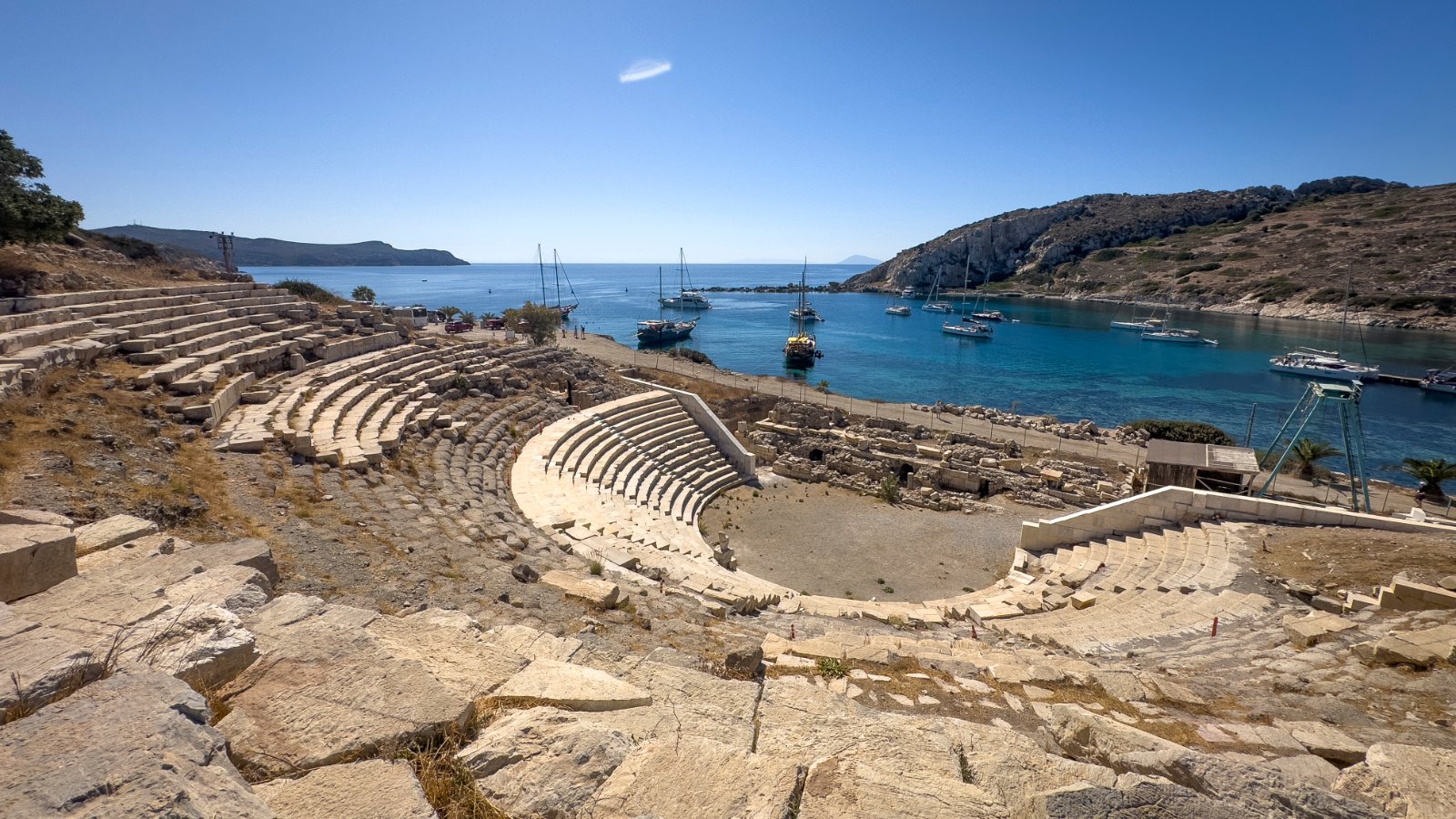 Anfiteatro antigo à beira do Mediterrâneo com navio ao fundo